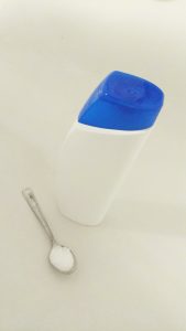 image of a tea spoon with MSM powder and white empty shampoo bottle