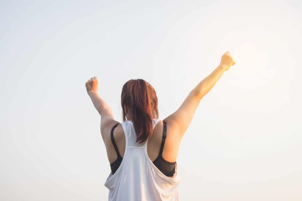 Image of a woman stretching her arms towards the sky in a victorious pose