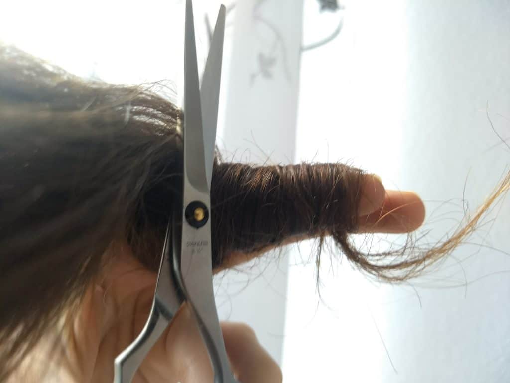 Image of a hair strand wrapped around a finger and hair shears