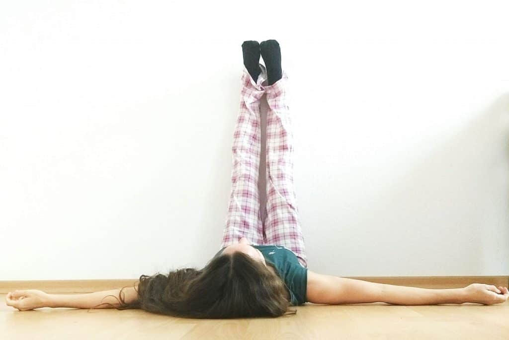 Image of a woman in Legs up the wall pose, a yoga pose very helpful for a clogged lymphatic system