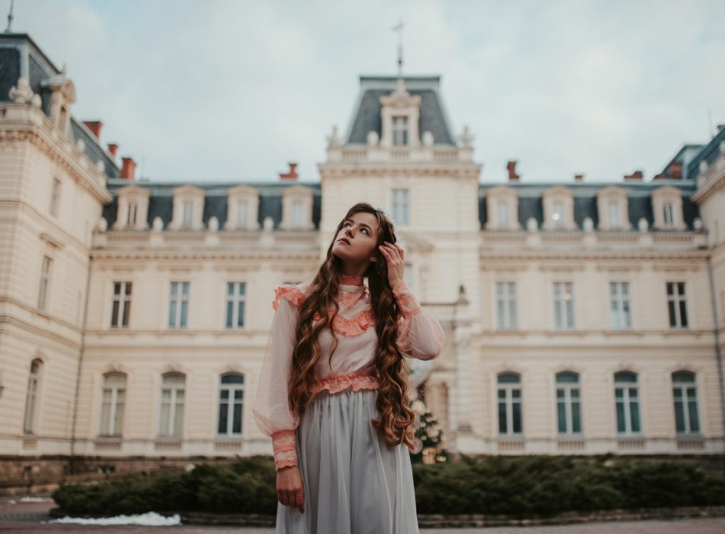 Image of a woman with very long hair standing in front of a historic building, looking up